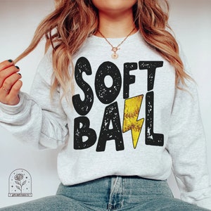 May include: A grey sweatshirt with the words "SOFTBALL" in black with a yellow lightning bolt graphic.