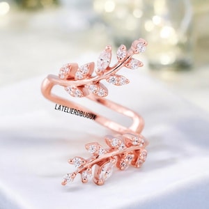 Può includere: Anello in oro rosa con due delicati rami adornati con scintillanti pietre di zircone cubico trasparenti. L'anello è progettato per essere indossato sul nodo o sul dito.