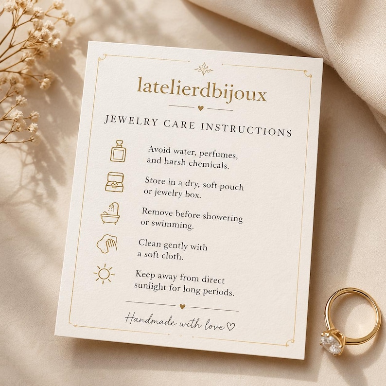 Puede incluir: Un anillo de oro con una piedra preciosa transparente junto a una tarjeta crema con instrucciones de cuidado de joyas. La tarjeta tiene el texto "latelierdbijoux" y "Handmade with love".