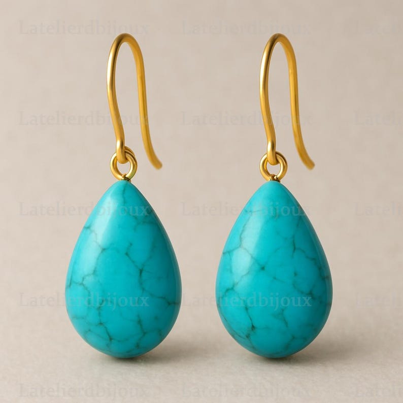 Puede incluir: Un par de pendientes turquesa en forma de l&aacute;grima con ganchos dorados. Las piedras turquesas tienen un aspecto veteado. Los pendientes se muestran sobre un fondo neutro. Joyer&iacute;a.