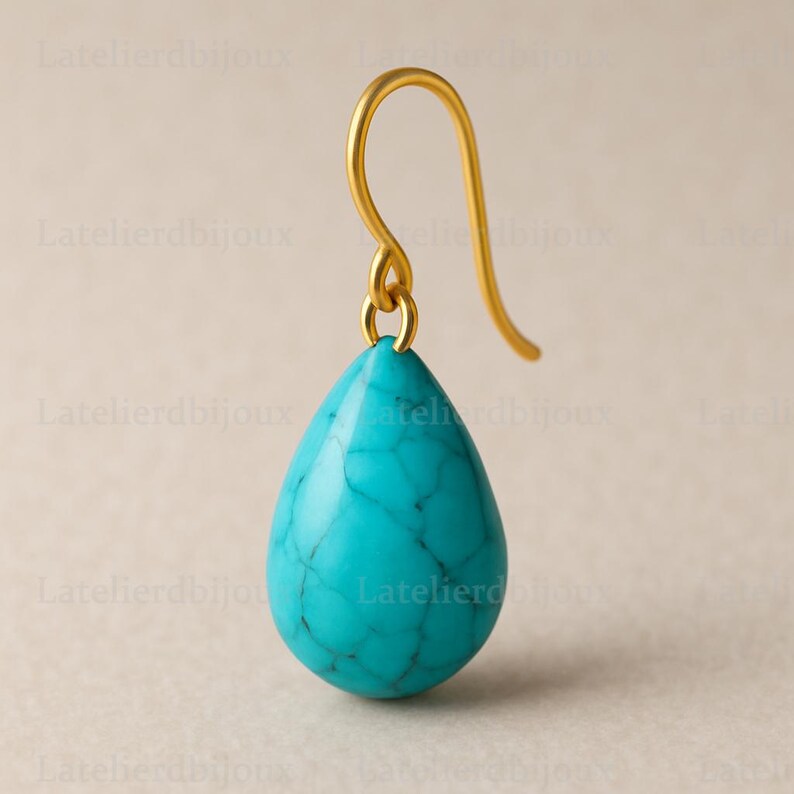Puede incluir: Un solo pendiente dorado con una piedra turquesa en forma de l&aacute;grima. La piedra tiene un aspecto veteado con vetas azul oscuro. El gancho del pendiente es curvo y sencillo.