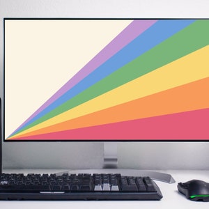 May include: A computer monitor displaying a rainbow-coloured background. The monitor is on a white desk with a black keyboard and a black mouse. There are two black speakers on either side of the monitor.