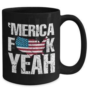 May include: A black ceramic mug featuring white distressed-style text that reads 'MERICA F K YEAH. The letter U in the word FUCK is replaced by a graphic of the United States map filled with the American flag pattern in red, white, and blue colors.