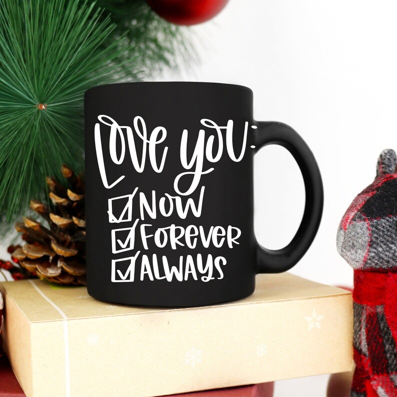 May include: Black ceramic coffee mug with white text that reads "Love you: Now, Forever, Always" with checkmarks next to each option.