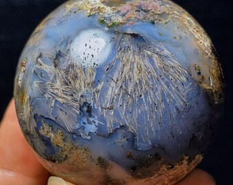 May include: A blue, brown and white agate sphere with a unique, dendritic pattern. The sphere is polished and has a smooth surface.