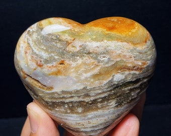May include: A heart-shaped stone with a swirling pattern of brown, white, and orange colors.