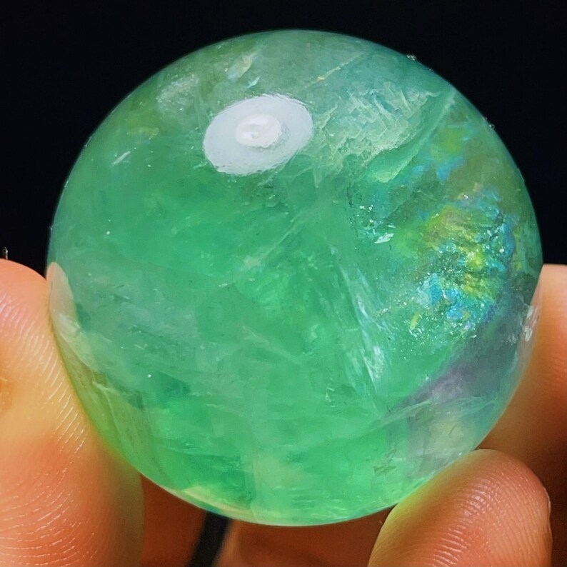 May include: A green fluorite sphere with a white centre. The sphere is smooth and polished, with a translucent appearance.