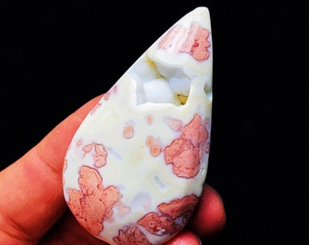May include: A teardrop-shaped pendant made of white and pink agate with a natural, organic pattern. The stone has a translucent quality and shows a variety of pink and white hues.