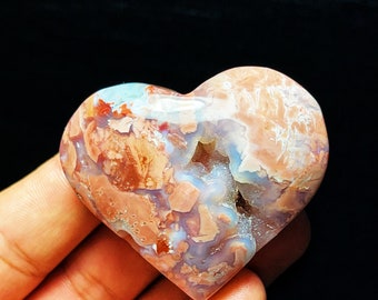 May include: A heart-shaped agate stone with a natural, polished finish. The stone features a mix of white, pink, and brown colors with a unique, swirling pattern.