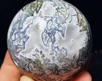 May include: A polished, white agate sphere with intricate, swirling patterns of gray and green. The sphere is smooth and has a high gloss finish.