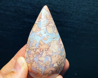 May include: A teardrop-shaped, polished agate stone with a unique, swirling pattern of pink, white, and brown. The stone has a smooth, glossy finish.
