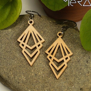 Peut inclure: Une paire de boucles d'oreilles en bois avec un motif géométrique. Les boucles d'oreilles sont en bois brun clair et ont un design en forme de diamant superposé. Les boucles d'oreilles sont suspendues à des crochets argentés.