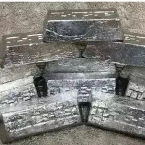 May include: A collection of silver metal bars, rectangular in shape, arranged in a pile. The bars have a textured surface and appear to be made of a solid metal. The image is taken from a slightly elevated angle, showing the tops and sides of the bars.