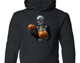 Peut inclure: Un sweat à capuche noir avec une impression graphique représentant un squelette portant une veste de costume noire. Le squelette tient deux citrouilles orange rondes, une dans chaque main, sur un fond sombre. Le sweat a des manches longues.