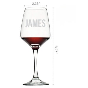 Custom-engraved wine glass with the name 'JAMES' on it, filled with red wine, dimensions labeled as 2.36 inches wide and 8.27 inches tall, against a white background.