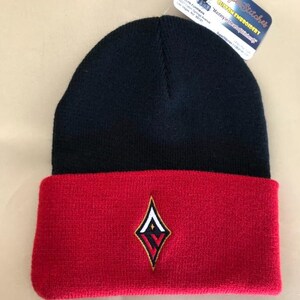 May include: A navy blue and red beanie hat with an embroidered diamond-shaped logo. The hat features a folded red brim and a tag with the text "Super Stitches Custom Embroidery".