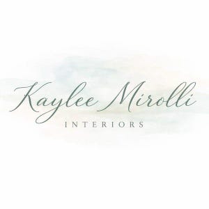 May include: A logo design featuring the text Kaylee Mirolli in a dark gray cursive script, with the word INTERIORS in a smaller, spaced-out sans-serif font underneath, all set against a soft, pale watercolor wash of blue and peach tones.