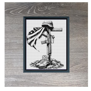 May include: Black and white cross stitch pattern of a fallen soldier with a helmet, rifle, and American flag. The pattern is framed and titled "Fallen Hero" with the dimensions 150 x 197.