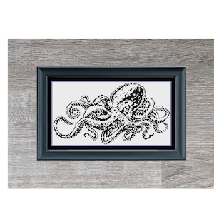 Könnte beinhalten: Schwarzweißes Pixel-Art-Bild eines Kraken in einem Holzrahmen. Das Bild trägt den Titel "Mini Octopus" und stammt von Stitching Jules Design.