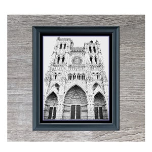 Könnte beinhalten: Schwarz-weiß-Zeichnung der Kathedrale Notre-Dame in Paris, Frankreich. Die Zeichnung ist in einem schwarzen Rahmen gerahmt und vor einem Holzmaserungshintergrund platziert.