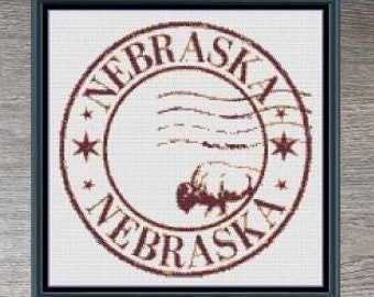 May include: Cross stitch pattern for a vintage-style stamp featuring the state of Nebraska with a buffalo silhouette and the text "NEBRASKA" in a red circle. The pattern is 145 stitches wide by 145 stitches high and uses 4 DMC colors.