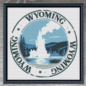 May include: Cross stitch pattern for a Wyoming state design. The pattern features a blue circle with a white outline and the text "WYOMING" in white. The circle contains a white silhouette of a geyser with a mountain range in the background. The pattern is 150 stitches wide by 150 stitches high and uses 11 DMC colors.