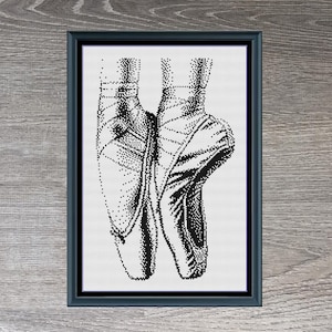Puede incluir: Patrón de punto de cruz en blanco y negro de un par de zapatillas de ballet. El patrón está enmarcado y el título "Ballet Shoes" está escrito debajo del marco. Las dimensiones del patrón son 119 x 191 puntos.