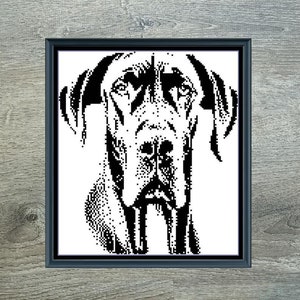 May include: A framed black and white cross-stitch pattern of a Great Dane dog. The artwork is titled "Mini Great Dane Monochrome" and measures 124 x 140 stitches. The design uses one DMC color and is set against a gray wooden background.