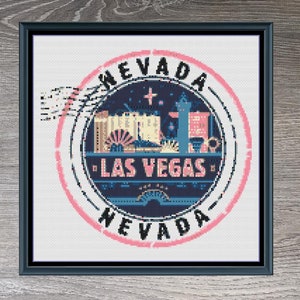 Könnte beinhalten: Gerahmtes Kreuzstich-Design mit einer kreisförmigen Las Vegas, Nevada, Grafik. Das Design zeigt den Text "Nevada" und "Las Vegas" in Rosa und Blau. Das Design misst 150 x 142 Stiche und verwendet 12 DMC-Farben.