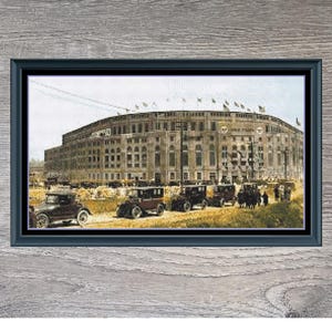May include: Framed print of the "Colorized Yankee Stadium" with a vintage aesthetic. The image features the stadium's exterior, classic cars, and a gray wooden frame. The print measures 245 x 135.