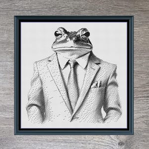 May include: Framed art print featuring a frog in a suit and tie, titled "Mr. Frog." The black and white illustration is set in a gray wooden frame. The artwork is from Stitching Jules Design.