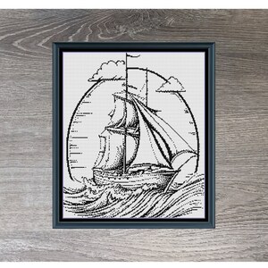 May include: Black and white cross stitch pattern of a sailboat on the ocean with clouds in the sky. The pattern is framed and the title "Sailboat Medium Monochrome" is below the frame. The dimensions are 180 x 210.