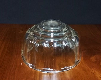 May include: A clear glass dessert mold with a fluted design. The mold has a rounded bottom and a wide, flat top.