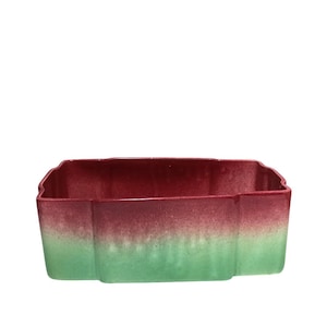 May include: A rectangular ceramic planter with a two-tone colour scheme. The top half is a deep red, transitioning to a light green at the bottom. The planter has a scalloped edge.