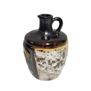 May include: A brown and white ceramic jug with a textured surface and a handle. The jug has a dark brown glaze on the top and a white glaze on the bottom.
