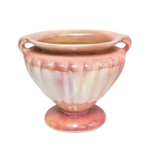 May include: A pink ceramic planter with two handles and a fluted design. The planter has a round base and a wide, open top.