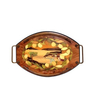 May include: Oval wooden serving tray with a decorative inlaid design. The tray features a landscape scene with lemons and a coastal village. The handles are a bronze colour. The tray is approximately 46 cm long.
