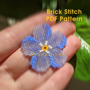 May include: A blue and white beaded flower with a yellow center. The flower is made using brick stitch and is labeled "Brick Stitch PDF Pattern".