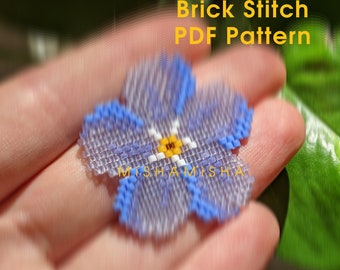 May include: A blue and white beaded flower with a yellow center. The flower is made using brick stitch and is labeled "Brick Stitch PDF Pattern".