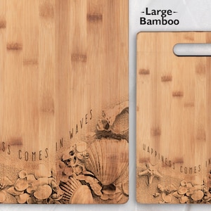 May include: Two wooden chopping boards with a beach theme. The larger board is labelled "Large - Bamboo" and the smaller board has the text "Happiness comes in waves" with a seashell design.
