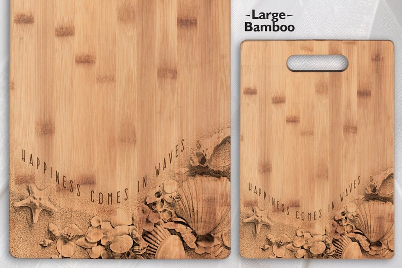 May include: Two wooden chopping boards with a beach theme. The larger board is labelled "Large - Bamboo" and the smaller board has the text "Happiness comes in waves" with a seashell design.