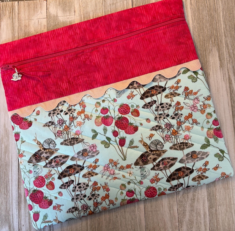 Pu&ograve; includere: Pochette con cerniera in tessuto trapuntato con parte superiore rossa e inferiore azzurra. Il tessuto inferiore presenta una stampa stravagante di fragole, lumache e funghi. Un bordo smerlato e una cerniera argentata completano il design.