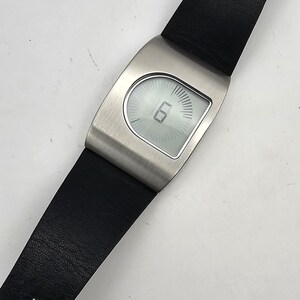 以下が含まれることがあります： シルバーカラーのケースと黒革バンドのモダンな腕時計。文字盤にはデジタル表示で時刻が表示されます。バンドにはシルバーのバックルが付いています。この時計は現代的なアクセサリーです。