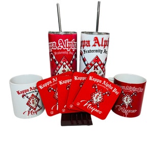 May include: A set of red and white themed Kappa Alpha Psi Fraternity Inc. merchandise. The set includes two tumblers with straws, four coasters, two mugs, and a chocolate bar. The tumblers and mugs feature the fraternity's logo and the words "Kappa Alpha Psi Fraternity Inc." and "Nupes". The coasters are red with the fraternity's logo and the words "Kappa Alpha Psi Fraternity Inc." and "Nupes".
