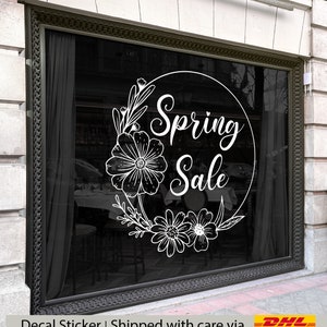 Może przedstawiać: Biała naklejka z wieńcem kwiatowym i tekstem "Spring Sale" w kółku na czarnym tle.