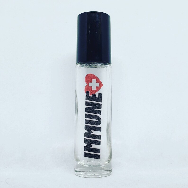 May include: A clear glass roller bottle with a black cap. The bottle has a white label with the word "IMMUNE" in black letters and a red heart with a white plus sign inside.