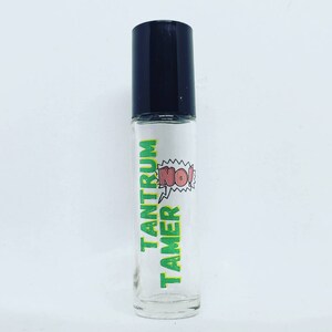 May include: A clear glass roller bottle with a black cap and a green and yellow label that says "Tantrum Tamer" with a red speech bubble that says "NO!"