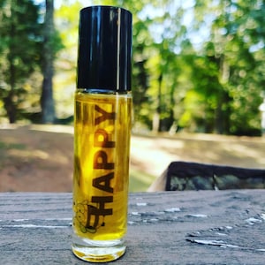 May include: A small glass bottle with a black cap and a yellow label that says "HAPPY". The bottle is filled with a clear liquid.