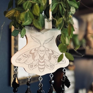 May include: A white ceramic mug with a black handle and the text "But First, Coffee" in a bold, black font. The mug is set against a blurred background, suggesting a cozy setting.