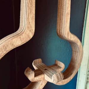 May include: A wooden wall-mounted phone holder shaped like an airplane. The holder is made of plywood and has a natural wood finish.
